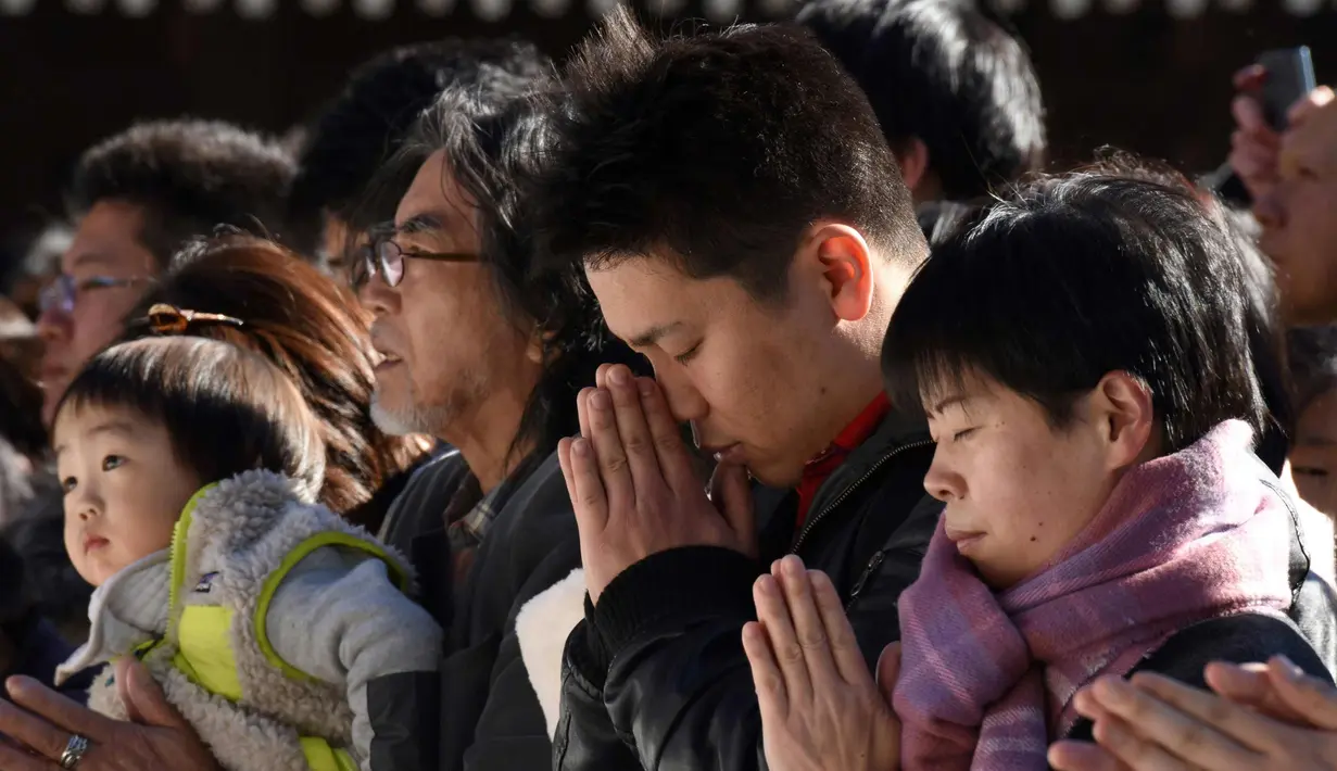 Warga memanjatkan doa Tahun Baru 2018 di Kuil Meiji, Tokyo, Jepang (1/1). Jutaan warga Jepang mengunjungi kuil-kuil di seluruh negeri selama tiga hari pertama tahun baru untuk berdoa demi kesejahteraan keluarga mereka. (AFP Photo/Kazuhiro Nogi)