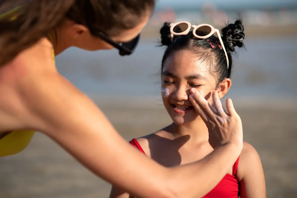 Seorang Ibu Sedang Mengoleskan Sunscreen Pada Anak