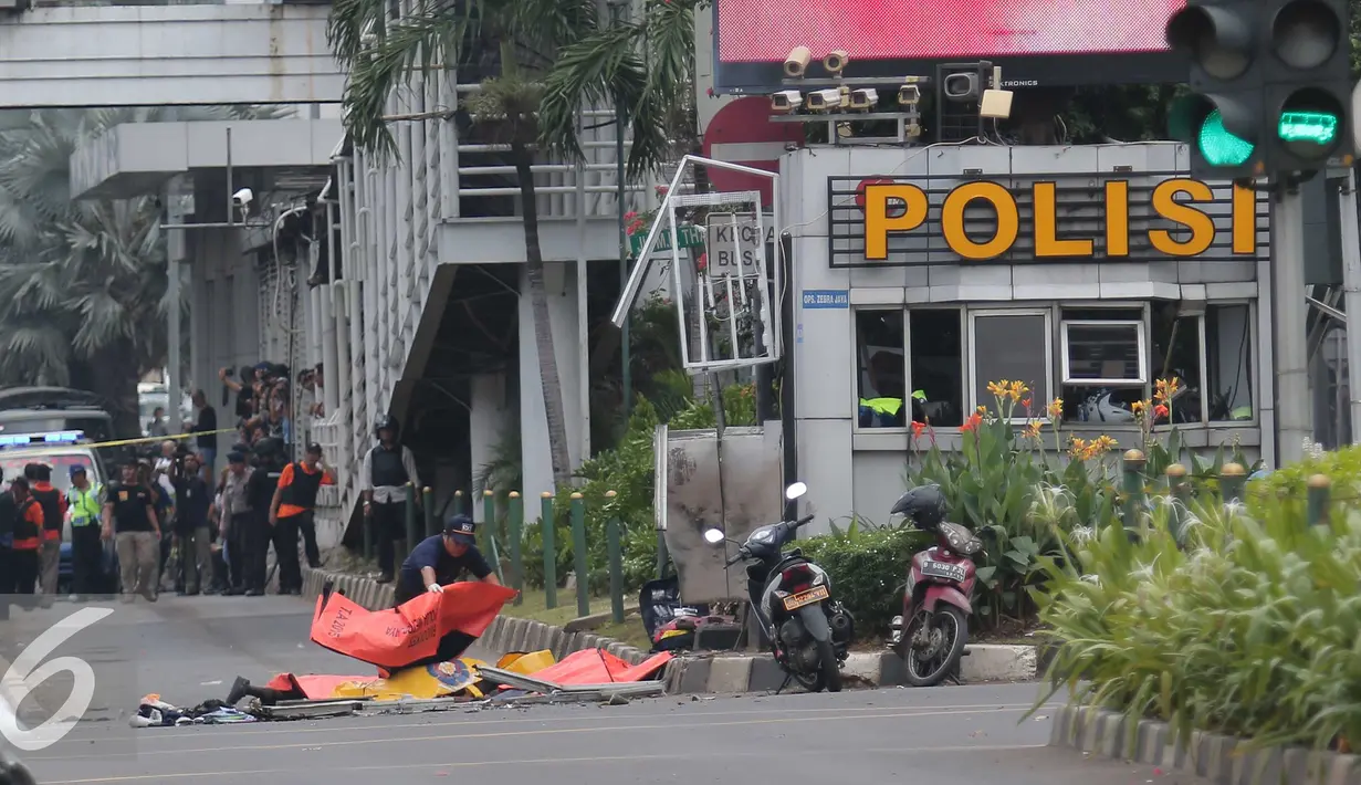 Petugas menutup mayat korban ledakan bom di pos pol sarinah, Jakarta, Kamis, (14/1/2016). Beberapa ledakan dan suara senjata api terjadi di pusat ibukota Indonesia, Polisi mencurigai seorang melakukan aksi bom bunuh diri. (Liputan6.com/Angga Yuniar)