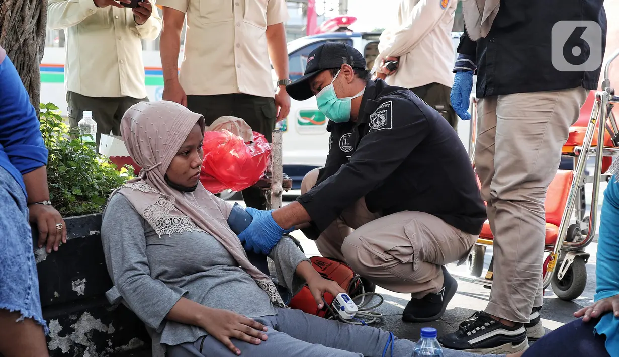 Petugas Dinas Kesehatan DKI Jakarta mengecek seorang warga yang mengalami pendarahan karena kelelahan saat CFD di Kawasan Bundaran HI, Jakarta, Minggu (14/8/2022). Warga tersebut langsung mendapatkan penanganan medis dan di bawa ke rumah sakit terdekat. (Liputan6.com/Angga Yuniar)