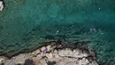 Orang-orang berenang di laut di pinggiran Vouliagmeni, barat daya Athena, Yunani, Kamis (29/7/2021). Gelombang panas membuat orang-orang berbondong-bondong ke pantai, air mancur umum, dan lokasi ber-AC. (AP Photo/Yorgos Karahalis)