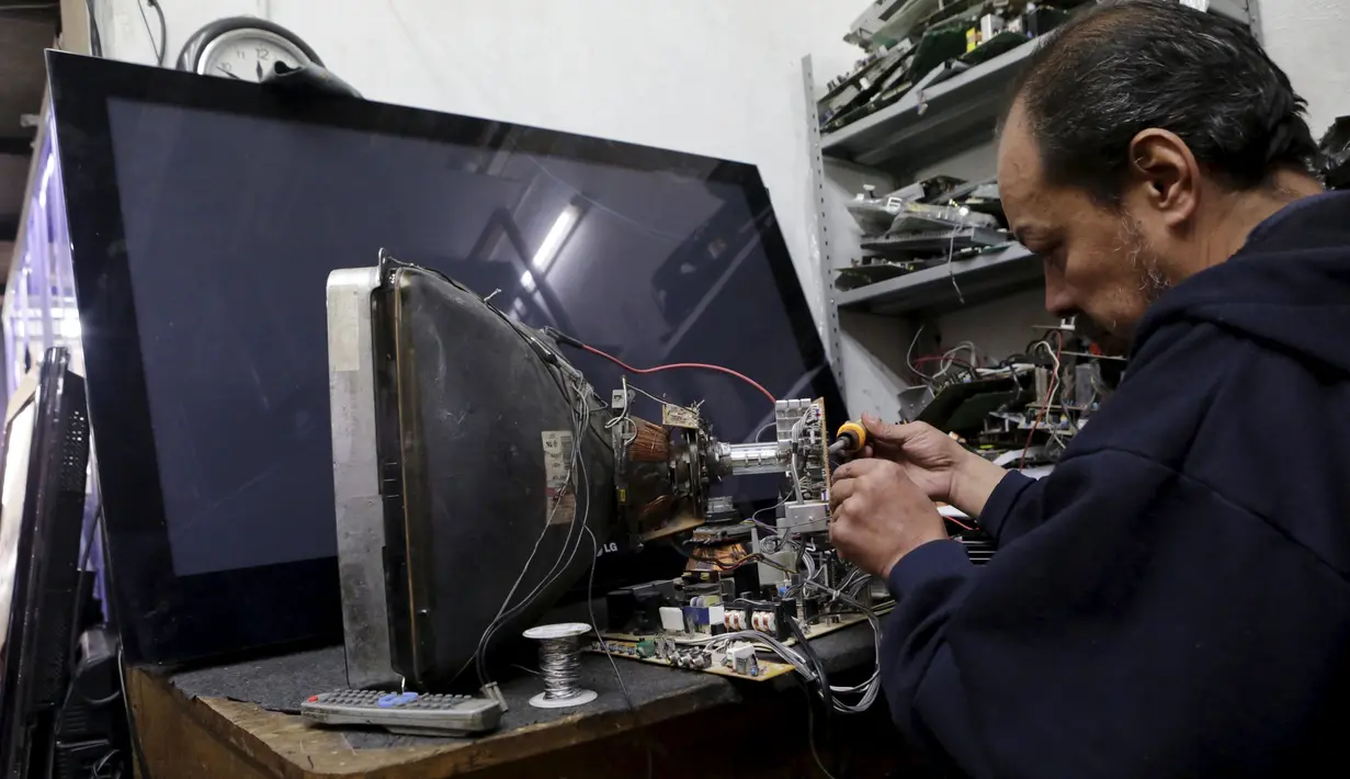 Seorang teknisi Tv saat memperbaiki Tv analog yang rusak, Mexico City, Meksiko, (16/12). Hal ini dalam upaya pergeseran teknologi yang dilakukan oleh pemerintah Meksiko. (REUTERS/Henry Romero)