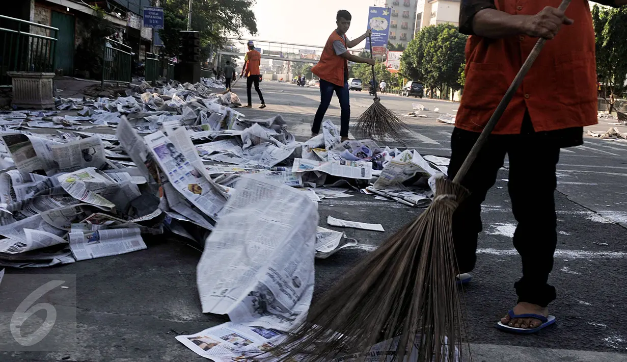 Petugas membersihkan sampah koran di ruas Jalan Jatinegara Barat, Jakarta, Jumat (17/7/2015). Lembaran koran bekas ditinggalkan begitu saja pasca pelaksanaan salat Hari Raya Idul Fitri 1436 H. (Liputan6.com/Johan Tallo)