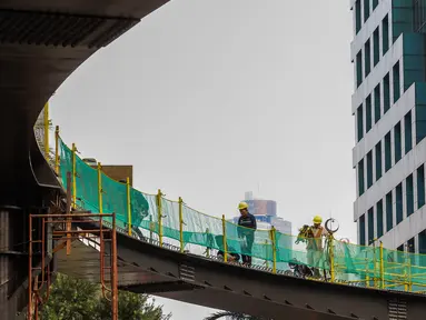 Pekerja menyelesaikan pengerjaan jembatan penyeberangan orang (JPO) dan jembatan penyeberangan sepeda di Karet Sudirman, Jakarta, Jumat (8/10/2021). JPO yang akan dilengkapi jalur sepeda dan terintegrasi dengan halte Transjakarta itu akan rampung pada November 2021. (Liputan6.com/Johan Tallo)