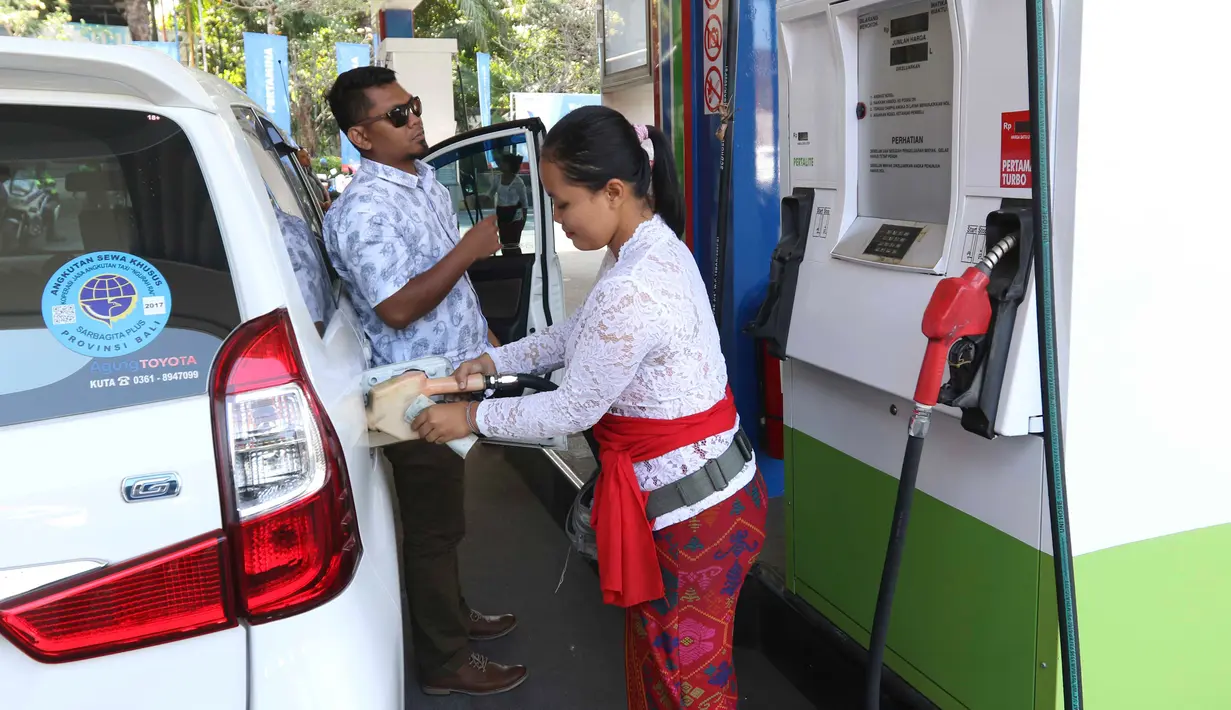 Petugas dengan pakaian adat mengisi bahan bakar minyak (BBM) ke sebuah mobil di SPBU, Bali, Rabu (10/10). Petugas SPBU mengenakan pakaian adat Bali untuk menyambut pertemuan tahunan IMF dan Bank Dunia. (Liputan6.com/Angga Yuniar)