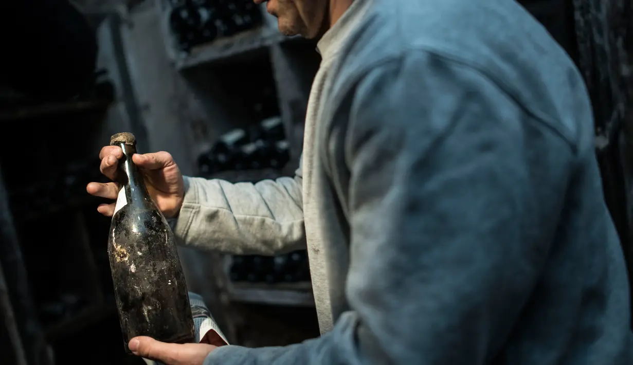 Seorang pria memegang botol anggur "Vin Jaune" tahun 1774 di Arbois, Perancis timur (22/5). Tiga botol anggur produksi tahun 1774 akan dijual pada 26 Mei 2018, selama lelang. (AFP Photo/Sebastian Bozon)