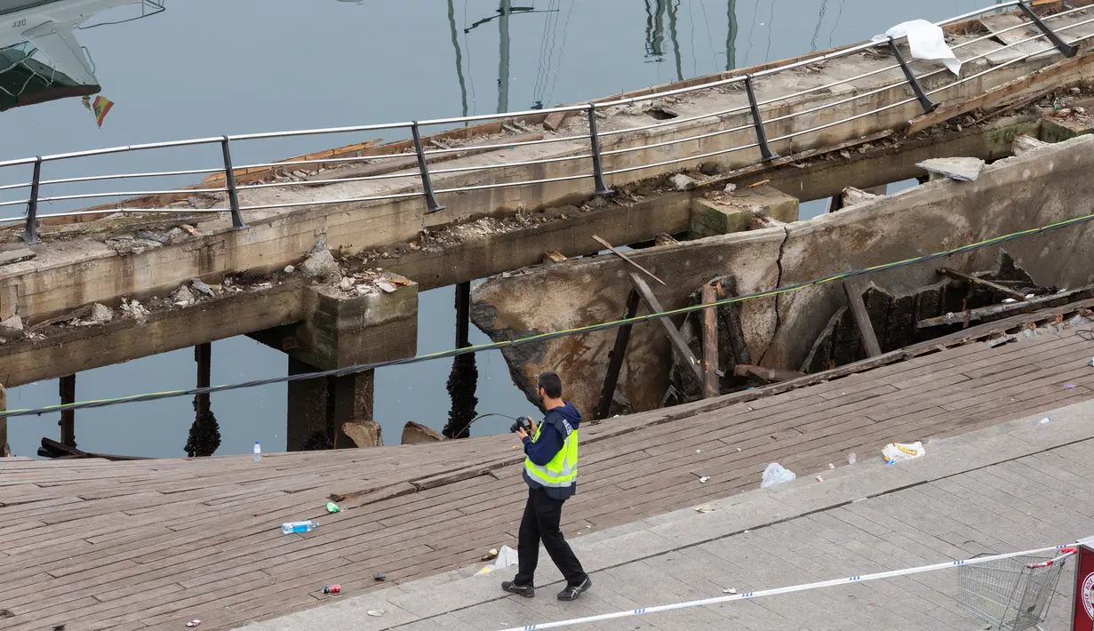 Petugas polisi mengambil foto di lokasi robohnya platform panggung dari kayu pada festival musik di tepi laut di Vigo, Spanyol, Senin (13/8). Festival musik tersebut memasuki hari kedua ketika insiden terjadi. (AP/Lalo R. Villar)