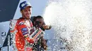 Pembalap Tim Ducati Corse, Andrea Dovizioso menyemprot sampanye saat merayakan kemenangannya di atas podium GP Inggris di Sirkuit Silverstone, Minggu (27/8). Dovizioso mengungguli dua pembalap Yamaha, Maverick Vinales dan Valentino Rossi. (OLI SCARFF/AFP)