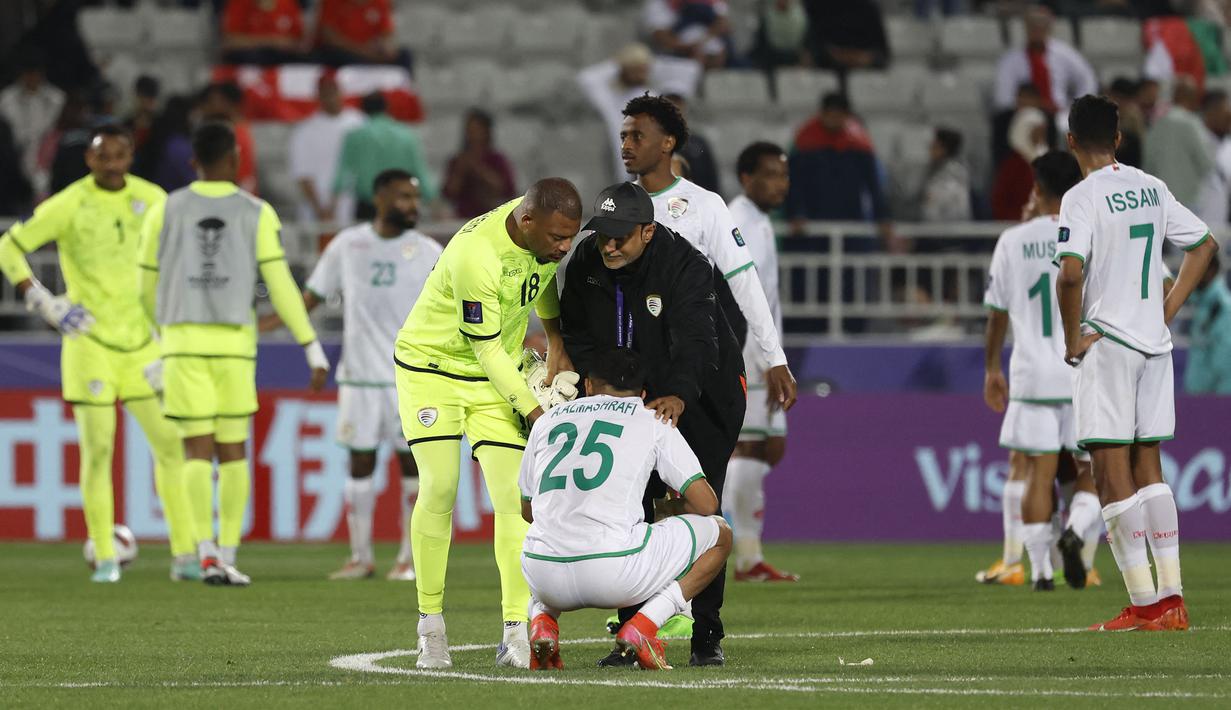 Kiper cadangan Timnas Oman, Faiyz Al Rusheidi dan seorang ofisial tim berusaha menghibur Abdullah Al Mushaifri (bawah) setelah bermain imbang 1-1 menghadapi Kirgistan pada laga ketiga Grup F Piala Asia 2023 di Abdullah bin Khalifa Stadium, Doha, Qatar, Kamis (25/1/2024) yang membuat Oman dan Kirgistan gagal lolos ke babak 16 besar. (AFP/Karim Jaafar)