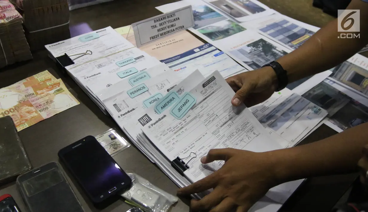Petugas menata barang bukti TPPU narkotika di kantor BNN, Jakarta, Selasa (26/1). Dalam kasus ini Petugas juga menyita 3 unit apartemen, 6 unit ruko, 1 unit rumah, 3 unit mobil, 2 unit toko dan uang senilai Rp 1,6 miliar. (Liputan6.com/Arya Manggala)