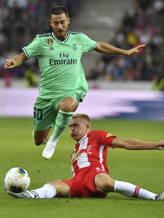 Gelandang Real Madrid, Eden Hazard berusaha melewati pemain Red Bull Salzburg, Rasmus Kristensen selama pertandingan persahabatan di Red Bull Arena, Austria (8/8/2019). Hazard datang ke Real Madrid dengan nilai transfer 100 juta euro. (AP Photo/Kerstin Joensson)