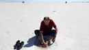 Seorang turis merendam kakinya di air Danau Tuz atau Tuz Golu yang surut di kota Ankara, Turki, 26 Agustus 2017. Pada saat libur musim panas, danau ini dikunjungi oleh para turis lokal sambil beredam untuk terapi kesehatan. (ADEM ALTAN/AFP)