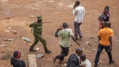 Aparat kepolisian memukuli pria saat membubarkan orang-orang yang masih berkeliaran di Kampala, Uganda (26/3/2020). Presiden Uganda Yoweri Museveni mengimbau masyarakatnya untuk tinggal di rumah selama 32 hari setelah 14 kasus positif Covid-19 teridentifikasi di negara tersebut. (AFP/Badru Katumba)