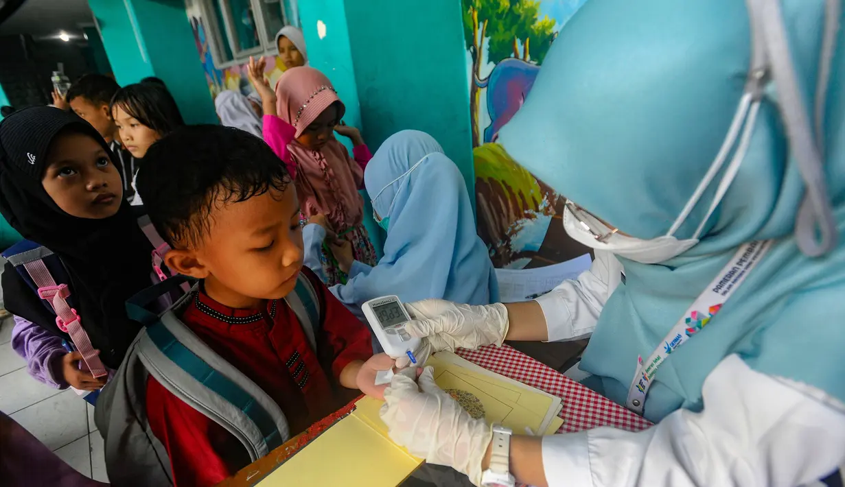 Tenaga medis dari Puskesmas Ciputat melakukan tes gula saat kegiatan pengecekan kesehatan murid di Sekolah Dasar Negeri (SDN) 04 Ciputat, Tangerang Selatan, Banten, Jumat (9/8/2024). (merdeka.com/Arie Basuki)