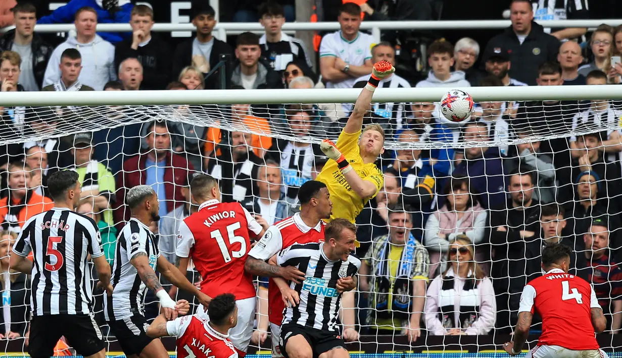 Penjaga gawang Arsenal, Aaron Ramsdale (tengah atas), berhasil menghalau bola serangan dari pemain Newcastle United dalam laga pekan ke-35 Premier League 2022/2023 yang berlangsung di St James Park, Minggu (7/5/2023). (AFP/Lindsey Parnaby)