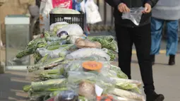 Seorang pria membeli sayuran di kios sayur tak berpenjaga di permukiman di Shijiazhuang, Provinsi Hebei, China utara (12/2/2020). Kios sayur tak berpenjaga itu didirikan untuk menyediakan sayuran kepada warga dengan kontak minimal sebagai upaya melawan epidemi virus corona. (Xinhua/Liang Zidong)