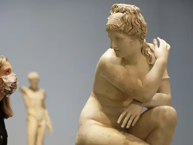 Seorang pegawai museum melihat ke arah patung marmer Crouching Venus, Romawi, abad ke-2 M, saat jumpa pers di The British Museum di London, Senin, (24/8/2020). Rute satu arah baru mengitari galeri Lantai Dasar akan memungkinkan pengunjung mengakses ribuan objek. (AP Photo/Kirsty Wigglesworth)