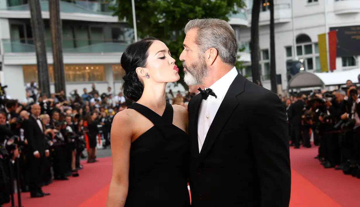 Aktor senior Mel Gibson dan pacarnya barunya saat berpose di karpet merah acara penutupan Festival Film Cannes ke-69 di Prancis, 22 Mei 2016. Pasangan romantis ini tak segan berbagi ciuman di depan umum. (Anne-CHRISTINE POUJOULAT/AFP)
