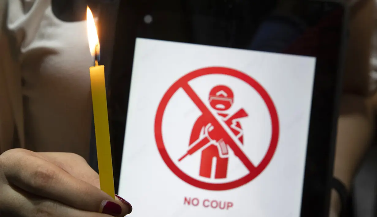 Warga Myanmar yang tinggal di Thailand memegang lilin saat protes di depan Kedutaan Besar Myanmar di Bangkok, Thailand, Kamis (4/2/2021). Warga membakar gambar Jenderal Min Aung Hlaing karena menjadi tokoh di balik kudeta militer Myanmar pada 1 Februari 2021. (AP Photo/Sakchai Lalit)