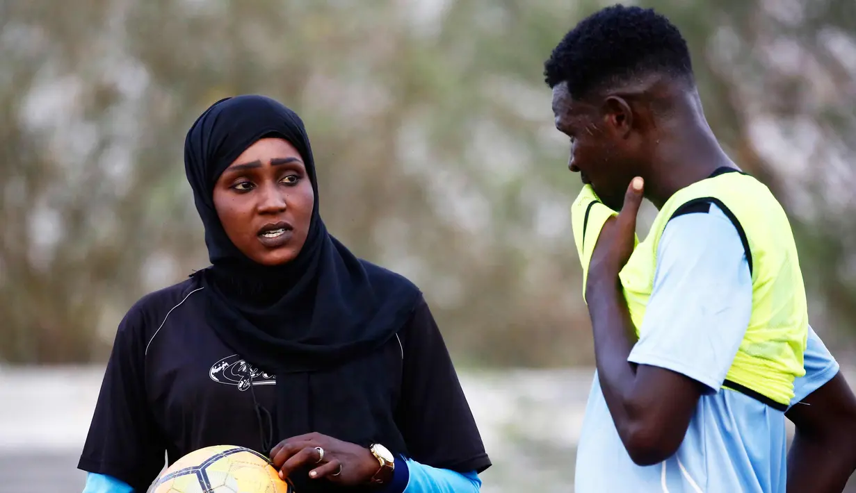 Salma al-Majidi berbincang dengan pemain klub Al-Ahly Al-Gadaref selama latihan di kota Gedaref, timur Khartoum (17/2). Salma tahu cara untuk mengambil bagian dalam olahraga yang dicintainya adalah melatih tim sepak bola pria. (AFP Photo/Ashraf Shazly)