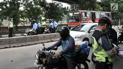 Polisi melakukan tilang terhadap pengendara yang melintasi jalur bus Transjakarta di Jalan Yos Sudarso, Jakarta, Senin (21/1). Razia rutin ini digelar untuk menjaring pengendara yang nekat menerobos jalur bus Transjakarta. (Merdeka.com/Iqbl Nugroho)