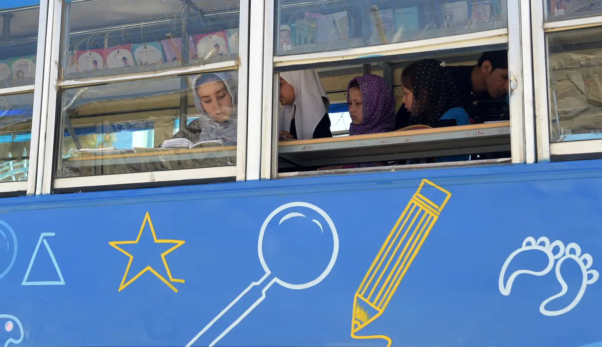 Anak-anak Afghanistan membaca buku dalam bus yang dijadikan perpustakaan keliling di Kabul, 4 April 2018. Charmaghz, nama bus keliling tersebut yang dalam bahasa setempat berarti 'kacang kenari', karena bentuknya menyerupai otak manusia. (AFP/Shah MARAI)