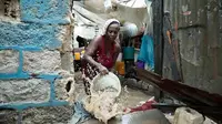 Seorang wanita menggunakan ember untuk mengeluarkan air dari dalam rumahnya yang terendam banjir, setelah hujan deras di Port-au-Prince, Haiti, Sabtu, 3 Juni 2023. (AP Photo/Odelyn Joseph)