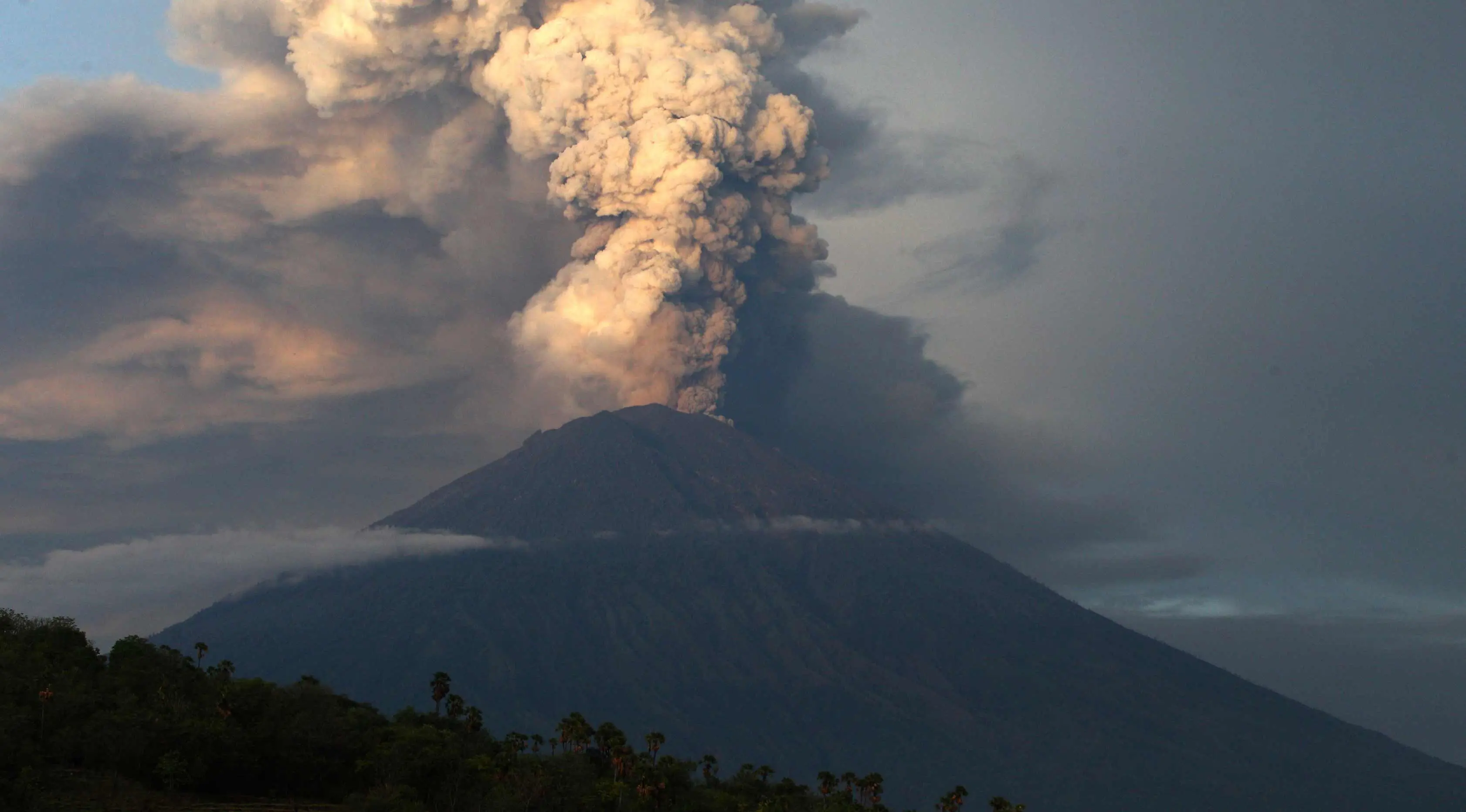 Pemandangan Gunung Agung yang mengeluarkan asap dan abu di Karangasem, Bali, Selasa, (28/11). Erupsi Gunung Agung yang masih terjadi menyebabkan Bandara Ngurah Rai ditutup. (AP Photo/Firdia Lisnawati)
