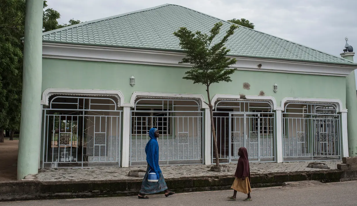 Warga melintasi masjid yang pernah diimami oleh pemimpin Boko Haram selama militan menduduki Kota Gwoza, Nigeria timur laut, (1/8). (AFP Photo/Stefan Heunis)