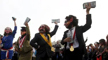 Para demonstran mengenakan kostum pejabat dan topeng sambil menghambur-hamburkan uang berunjuk rasa anti korupsi untuk memprotes pencalonan presiden Peru, Keiko Fujimori di Kota Lima, Peru (5/4). (REUTERS/Guadalupe Pardo)