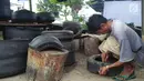Agus Baiku mengolah ban bekas menjadi produk berkelas di Desa Pentadio Barat, Kabupaten Gorontalo, Senin (31/12). Ban mobil bekas ditempat ini diubah menjadi tempat sampah, loyang, ayunan anak-anak serta pot bunga. (Liputan6.com/Arfandi Ibrahim)