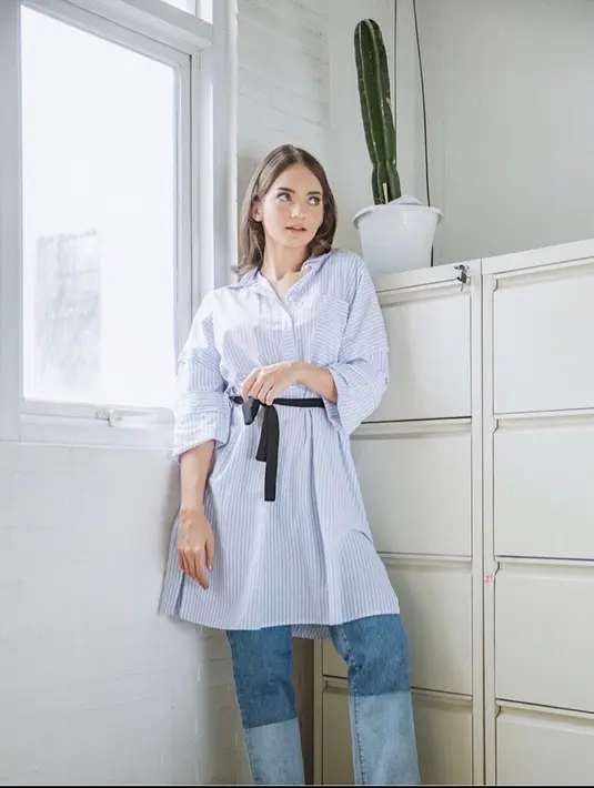 Kemeja tunik dengan motif striped berwarna biru putih sangat cocok untuk dipadu padankan dengan celana jeans two tones dapat menjadi outfit kantor andalanmu. (instagram/enzystoria)