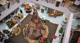 Salah satu mahasiswa berdiri di samping instalasi dekorasi berbentuk pohon Natal dengan motif budaya Papua di Perpustakaan Petra Christian University (PCU), Surabaya, Jawa Timur, Kamis 18 Desember 2025. Jelang perayaan Natal 2025, perpustakaan Petra Christian University (PCU) kembali menghadirkan instalasi dekorasi Pohon Natal tematik. (JUNI KRISWANTO/AFP)