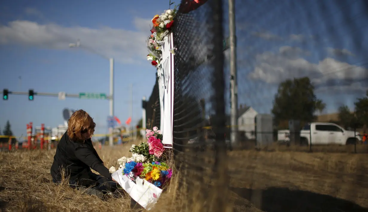 Seorang wanita menaruh bunga saat melakukan aksi simpatik mengenang korban penembakan di Kampus Umpqua Community College di Roseburg, Sabtu (3/10/2015). Setidaknya 15 orang tewas dalam peristiwa tersebut. (REUTERS / Lucy Nicholson)