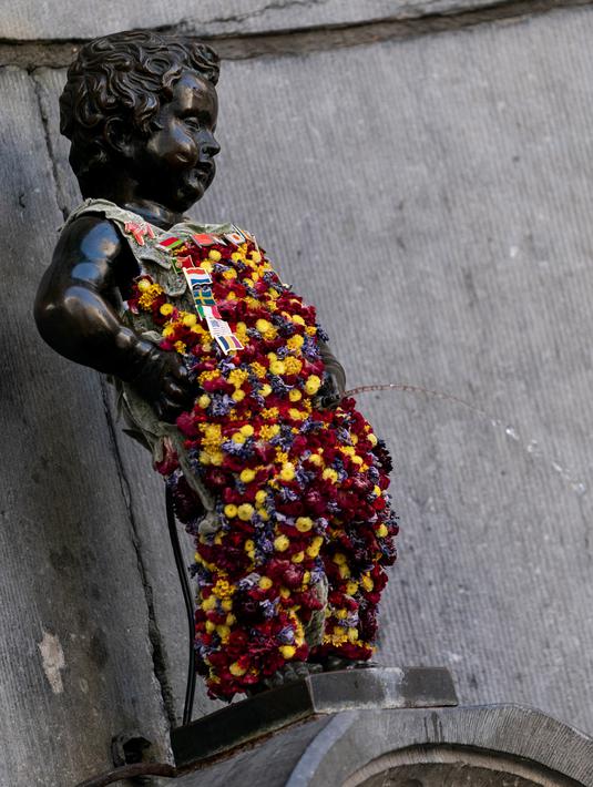 Gambar pada 12 Agustus 2019 memperlihatkan patung 'Manneken Pis' dalam balutan baju bermotif bunga di ibu kota Belgia, Brussels, Senin (12/8/2019). Patung perunggu yang hanya berukuran 60 sentimeter ini berwujud bocah lelaki yang sedang buang air kecil. (Photo by Kenzo TRIBOUILLARD / AFP)