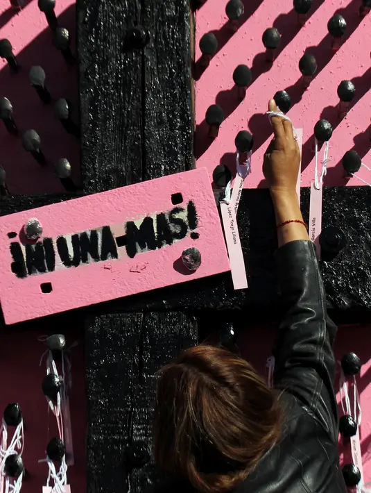 Aksi seorang ibu dan aktivis menempatkan nama-nama wanita yang dibunuh di Ciudad Juarez pada sebuah salib hitam di Jembatan Internasional Paso del Norte, Ciudad Juarez, Chihuahua, Meksiko, Rabu (7/3). (HERIKA MARTINEZ/AFP)