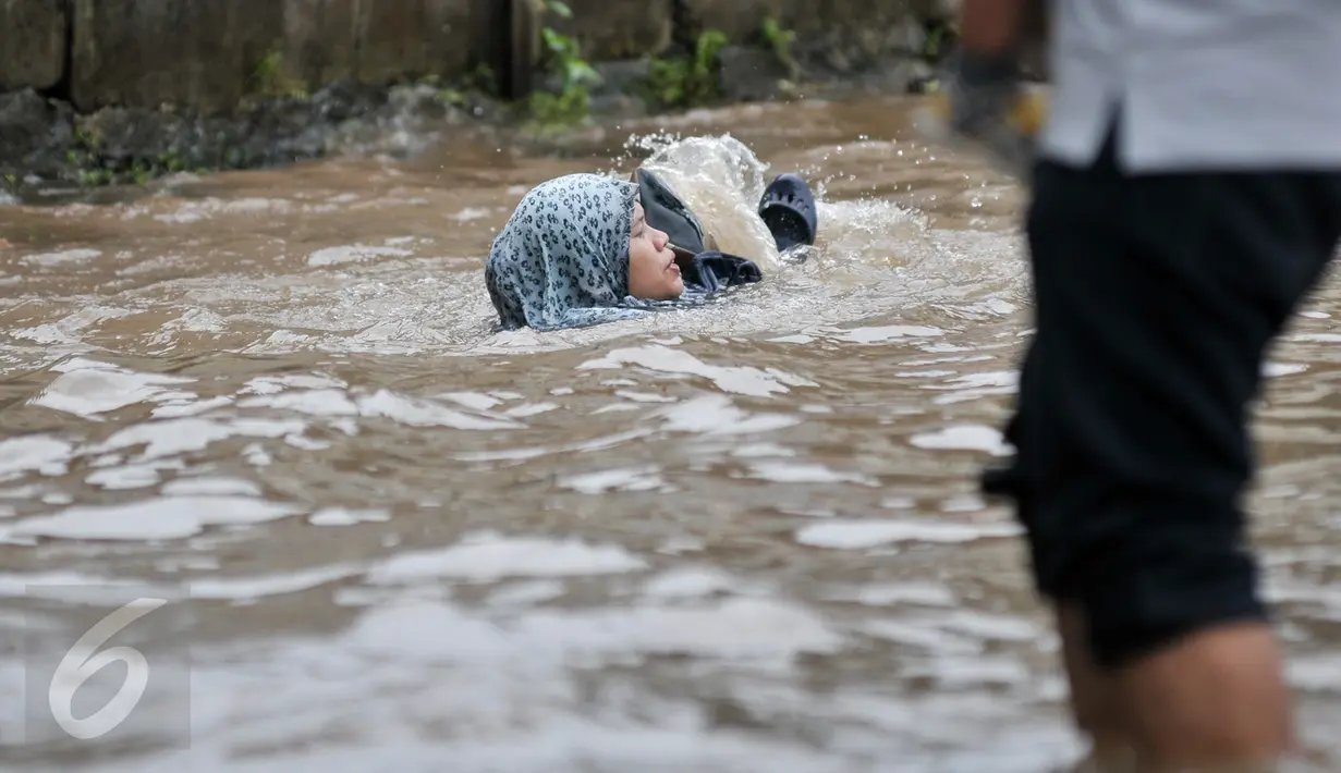 Seorang wanita terperosok ke dalam lubang saat melintasi banjir di Jalan Taman Bukit Duri, Jakarta Selatan, Selasa (21/2). Banjir yang menutupi jalan membuat lubang tak terlihat. (Liputan6.com/Yoppy Renato)