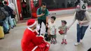 Pekerja yang mengenakan kostum Sinterklas berkomunikasi dengan anak-anak saat membagikan hadiah Natal kepada penumpang kereta cepat Whoosh. (Liputan6.com/Herman Zakharia)