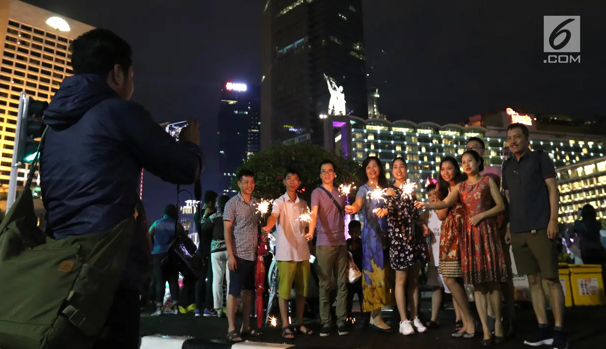 Warga menyalakan kembang api saat car free night pada malam pergantian tahun di Jalan MH Thamrin, Jakarta, Senin (31/12). Hujan yang mengguyur Jakarta sejak siang tidak menyurutkan antusias warga menikmati car free night. (Liputan6.com/Angga Yuniar)