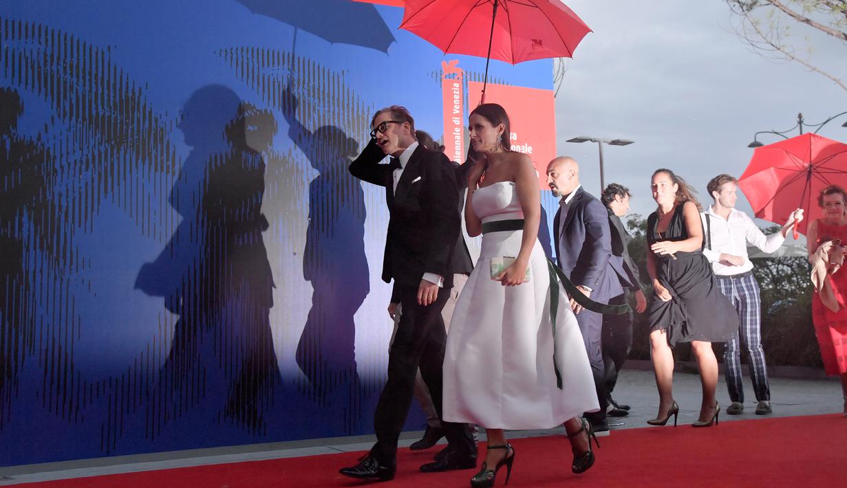 Aktor Colin Firth dan istrinya Livia Giuggioli saat menghadiri "Franca Sozzani Award" selama Festival Film Venice ke-74 di Venesia, Italia, (1/9). Angin dan Hujan membuat karpet merah di acara tersebut tergenang air. (AP Photo / Domenico Stinellis)