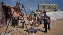 Anak-anak pengungsi Palestina bermain ayunan di sebuah kamp tenda selama Hari Raya Idul Adha di Khan Younis, Jalur Gaza Selatan, Rabu 27 Mei 2026. (AP Photo/Abdel Kareem Hana)