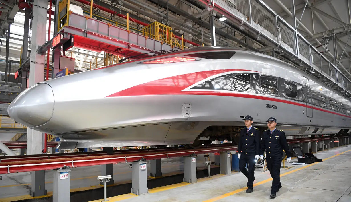 Dua mekanik berjalan melewati sebuah kereta peluru Fuxing CR400AF di stasiun pemeliharaan depo gerbong kereta di Kota Chongqing, China barat (23/12/2020). Kereta yang dioperasikan di Chongqing Railway untuk pertama kalinya, melakukan debut di Chongqing pada Rabu (23/12). (Xinhua/Tang Yi)