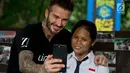 Mantan pesepakbola David Beckham berswafoto dengan siswi SMPN 17 Semarang, Sripun dalam kunjungannya sebagai Duta Kehormatan UNICEF ke Jawa Tengah, Rabu (28/3). Bersama Unicef, Beckham tengah melakukan kampanye anti-perundungan. (Liputan6.com/Pool/UNICEF)