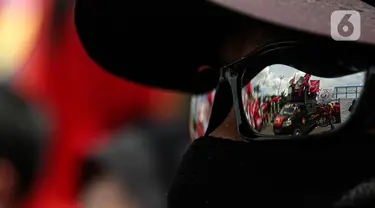 Aksi unjuk rasa buruh terefleksi dari kacamata massa yang menggeruduk gedung DPR RI, Jakarta, Selasa (10/1/2023). Dalam aksinya mereka menyuarakan penolakan terhadap Peraturan Pemerintah Pengganti Undang-Undang (Perppu) Cipta Kerja karena dinilai telah mengkhianati konstitusi. (Liputan6.com/Faizal Fanani)