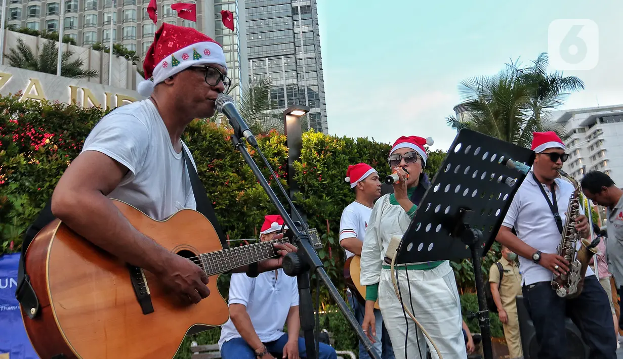 Musisi mengelar pertunjukan musik bernuansa Natal di jalur Pedestrian Bundaran HI, Jakarta Pusat, Selasa (20/12/2022). Pergelaran musik bernuansa Natal tersebut sebagai bentuk pertunjukan untuk menghibur warga yang melintas di Kawasan itu. (Liputan6.com/Angga Yuniar)