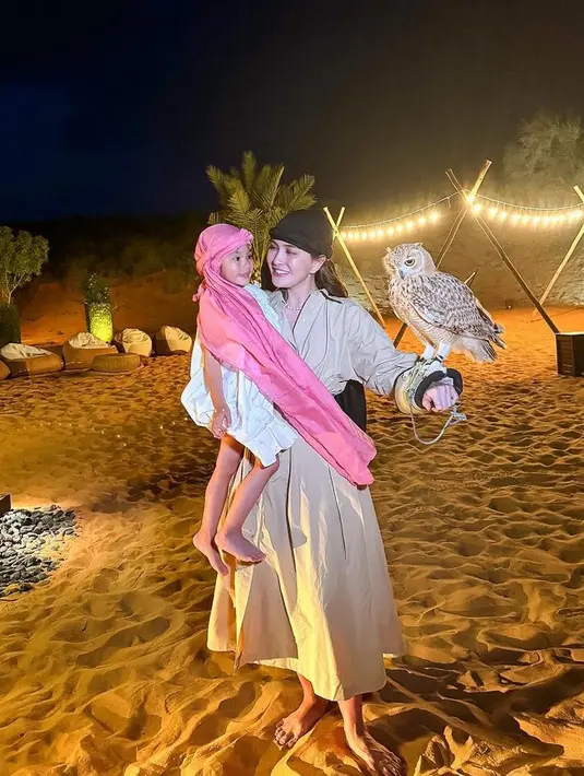 Shandy Aulia juga memanfaatkan momentum libur lebaran dengan mengajak putrinya liburan ke Dubai. Berada di padang pasir, Shandy mengenakan dress coklat lengan panjang, dan putrinya dibalut dress putih dan sorban pink. [@shandyaulia]