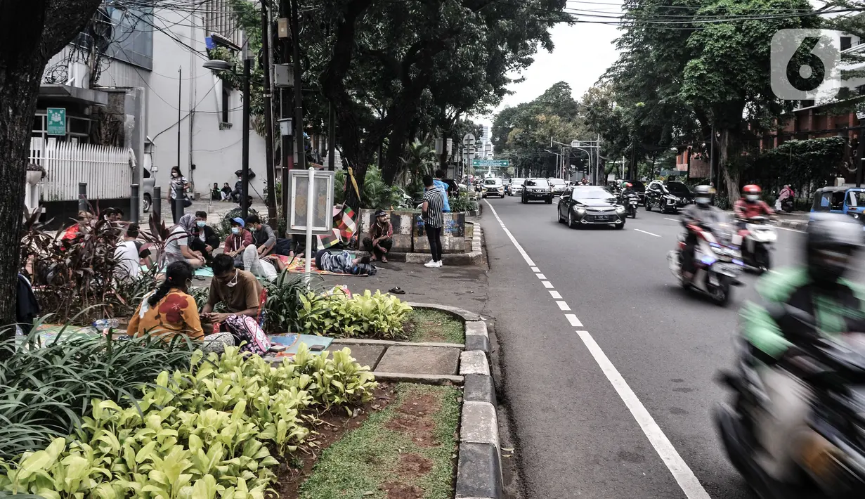 Kendaraan melintas di dekat imigran pencari suaka yang menghuni di depan Kantor UNHCR Kebon Sirih, Jakarta Pusat, Kamis (1/4/2021). Puluhan imigran dari berbagai negara konflik kembali menghuni di depan Kantor UNHCR Kebon Sirih sejak beberapa waktu lalu. (merdeka.com/Iqbal S Nugroho)