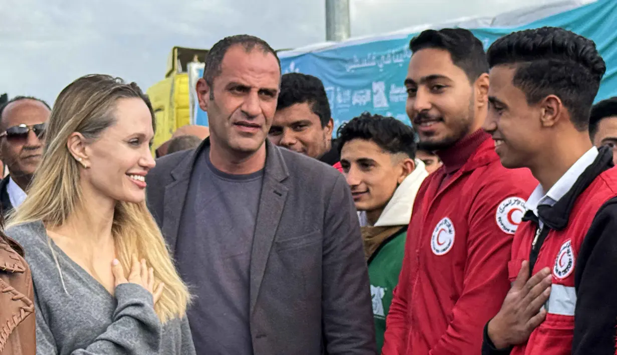 Diketahui, saat ini, Gaza sedang menghadapi musim dingin yang ekstrem, dengan hujan lebat dan penurunan suhu yang memperburuk kondisi para pengungsi. Tampak dalam foto, aktris Amerika Serikat (AS), Angelina Jolie (kiri) menyapa seorang karyawan Bulan Sabit Merah Mesir di perbatasan Rafah Mesir, pada Jumat 2 Januari 2026. (Foto oleh AFP)