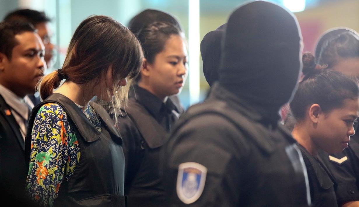 Tersangka kasus pembunuhan Kim Jong-nam, Siti Aisyah dan Doan Thi Huong, dikawal polisi menuju Bandara Internasional Kuala Lumpur, Selasa (24/10). Keduanya melakukan reka ulang kejadian di tempat keduanya dituding meracuni Kim Jong-nam. (AP/Sadiq Asyraf)