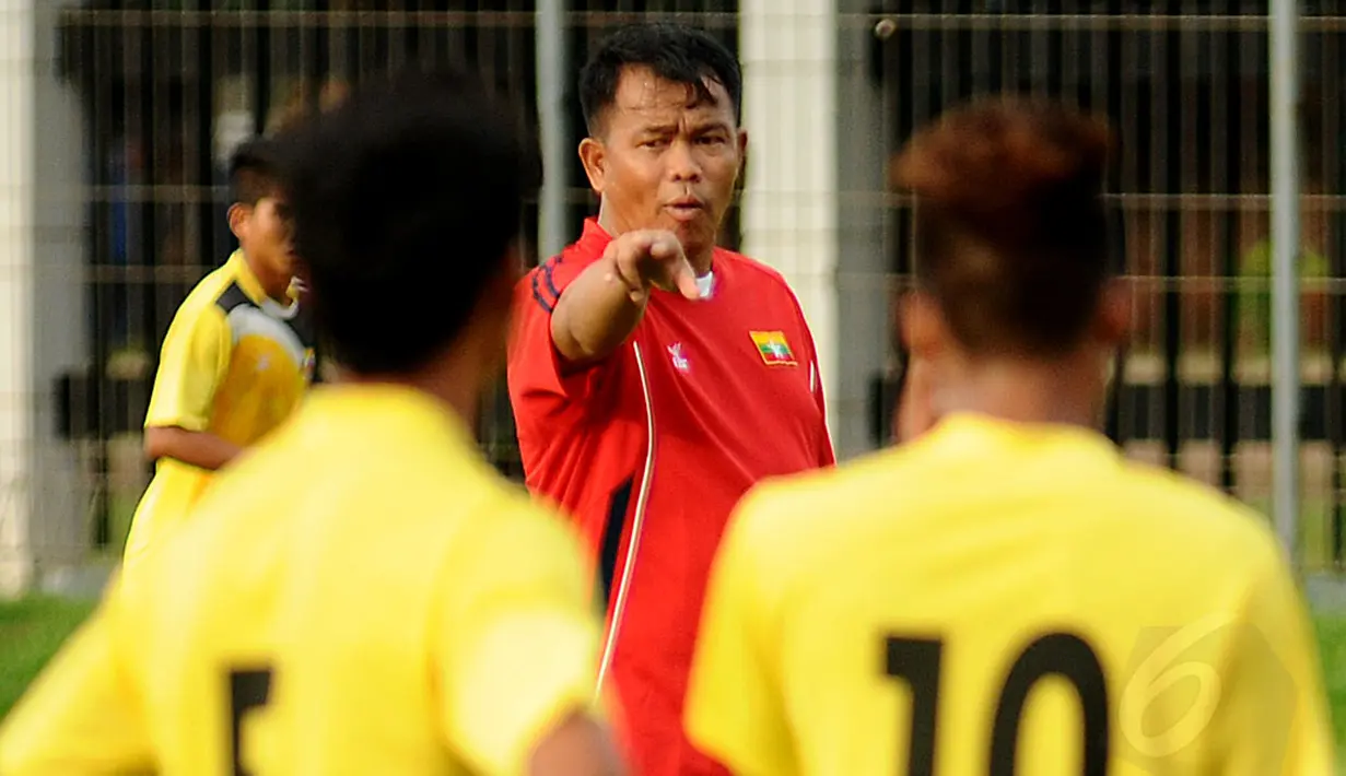 Asisten pelatih Timnas Myanmar U19, Nyi Nyi Latt (berbaju merah) terlihat memberikan instruksi pada dua anak didiknya saat berlatih di lapangan C Senayan Jakarta, Minggu (4/5/2014). (Liputan6.com/Helmi Fithriansyah)